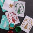 Four holiday cards with Harry Potter-themed designs in green, red, and gold ink are displayed on a dark surface, along with a teal ink pad, a jar of green paint, and a teal instruction sheet.