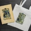 A spiral notebook and a white tote bag, each featuring vintage-style illustrations of scenes from Harry Potter, are placed on a dark surface.