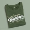 A folded green T-shirt with “Try Quidditch, Go Flying Today!” and a broomstick graphic printed on the front. Text is in white with a golden snitch illustration above.