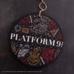A round sign with “PLATFORM 9 ¾” in white text is decorated with Harry Potter-themed drawings, including a train, broom, owl, books, and magic items, all outlined in white, red, and yellow on a black background.