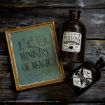 Framed "Ministry of Magic" sign next to two dark potion bottles labeled "Hogwarts Potions" and "Charms" on a rustic wooden surface.