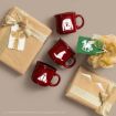 Three red mugs with Harry Potter designs are arranged among two wrapped gifts with gold ribbons and themed tags, all set on a beige background.