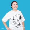 A smiling woman stands against a blue background, wearing a white T-shirt featuring large illustrations of Snoopy and Woodstock from Peanuts.