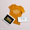 A mustard yellow “Sarcasm Society” T-shirt, a framed Peanuts comic print with characters in a pumpkin patch, and a rectangular dish with a Lucy illustration and “LAUGH” text, all on a light surface.
