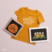 A gold t-shirt reads “The Sarcasm Society” beside two framed Peanuts prints: one with a pumpkin and text, and another showing Peanuts characters in a pumpkin patch.