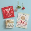 Gift items including a wrapped present with a gold ribbon, two festive signs, and three holiday ornaments on a light blue background.