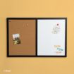 A black-framed board with a cork side holding a photo and a whiteboard side with a note and colorful “THINK” words, mounted on a yellow wall.