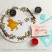 A round wooden tray features Pooh and Piglet with holly accents. Nearby are red paint, a card reading “WARM & COSY” with Piglet, Chalky Finish paste, a brush, and a blue card with a reindeer design.