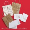 Three paper gift bags and four sheets of paper with brown and red sketches of Winnie the Pooh and friends on a red background. Gift bags have rope handles and feature various holiday-themed designs.