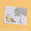 A mat featuring Winnie the Pooh pulling Piglet in a wagon filled with apples, beside an apple tree, on a pastel yellow background.