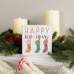 A festive sign reading “Happy Holidays” with three stockings, surrounded by evergreen branches, red berries, candy canes, and lit candles.