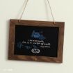 A small chalkboard with a wooden frame hangs on a wall. It features a quote: “I live in two worlds, One is a world of books. -Rory Gilmore” with blue drawings of books and leaves.