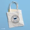 A white tote bag with “Life’s Short Talk Fast” and a blue butterfly printed on it, along with “Gilmore Girls.” A yellow folder is partially visible inside. The bag is on a light blue background.