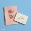 A pink spiral notebook with a coffee cup illustration beside a cream card labeled “Coffee, Coffee, Coffee” on a light blue background.