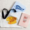 White tote bag with “Luke’s” and a yellow coffee cup, a blue “Chilton” folder, and a pink notebook with a coffee cup and handwritten notes, all displayed on a light surface.