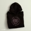 A folded black hoodie with a pink design featuring an open book, the words “Gilmore girls,” and the text “Sip Coffee Read Books” in a circular layout.