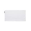 A plain rectangular white cloth napkin is laid flat with a small black tag on the left edge. The background is white.