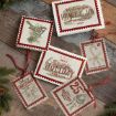 Six vintage-style Christmas cards and tags with holiday greetings, festive images, and red ribbon, arranged on a rustic wooden surface with evergreen branches nearby.