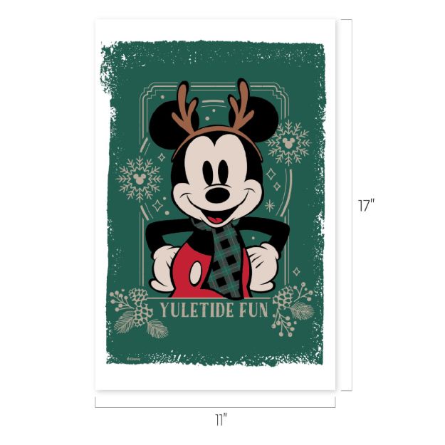 Mickey Mouse wearing antlers and a scarf stands in front of a green background with snowflakes and pinecones. Text at the bottom says “YULETIDE FUN.” Image size is 17 inches by 11 inches.