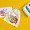 A cream drawstring bag with a Santa Mickey Mouse design next to a matching printout and a heat press on a yellow surface. Mickey holds a letter by a red mailbox. Disney copyright is visible.