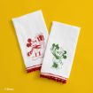 Two white towels on a yellow background feature red and green line drawings of Mickey Mouse and Minnie Mouse holding gifts. Red pom-pom trim decorates the towel edges.