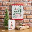 A Disney-themed holiday setup with a small tree, a gift, a card featuring a tree made of Mickey Mouse icons, and a sign with Mickey and Minnie reading “Oh so much more Holly!” against a brick wall.