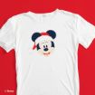 A white T-shirt featuring Mickey Mouse wearing a red Santa hat, displayed on a vibrant red background.