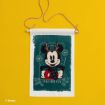A festive wall hanging featuring Mickey Mouse wearing antlers and a scarf, with snowflakes and the text “Yuletide Fun” on a green background, set against a bright yellow surface.