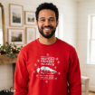 A smiling man wearing a red sweatshirt that reads “Griswold Family Vacation” with a graphic of a station wagon carrying a Christmas tree.