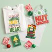 Elf-themed merchandise including a white sweatshirt, a canvas tote bag, and two small wooden signs with holiday quotes and imagery, surrounded by three ornaments.