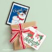 A framed print of Frosty the Snowman titled “The Original” next to a gift-wrapped box with a tag that says “It Must Be Magic” featuring Frosty the Snowman.